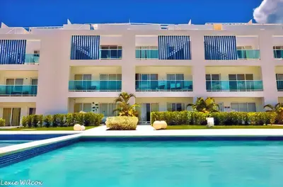 a hotel with a swimming pool in front of a building at Cana Rock Condos Familiar - Two apartments very close-Ground floor direct access to the pool in Punta Cana