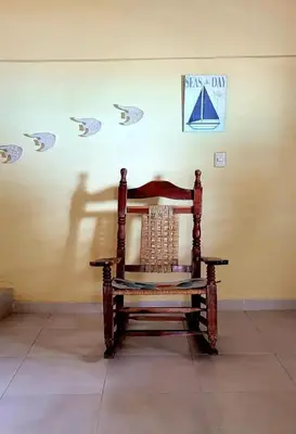 a wooden chair in a room with a wall with a sailboat on it at La Casita de Mary in Santa Cruz de Barahona