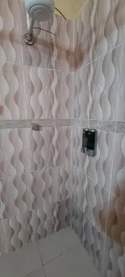 a bathroom with a pink tiled wall with a light at La Casita de Mary in Santa Cruz de Barahona