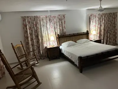 a bedroom with a bed and a chair and curtains at Villa La Esperanza in Nizao