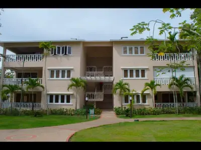 a large building with palm trees in front of it at Delightful Caribbean apartment in Boca Chica in Boca Chica