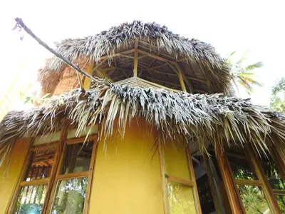 a straw roof on a building with windows at Tropical Cottage En Eco Casa Algana in El Limón