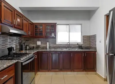 a kitchen with wooden cabinets and a sink and a window at Escape 3BR Apartment in the Heart of Piantini Nightlife in Santo Domingo
