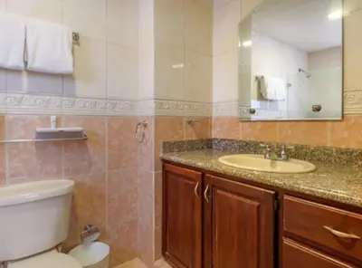 a bathroom with a toilet and a sink and a mirror at Escape 3BR Apartment in the Heart of Piantini Nightlife in Santo Domingo