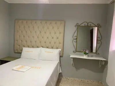 a bedroom with a white bed and a mirror at Glamour Hotel in La Romana