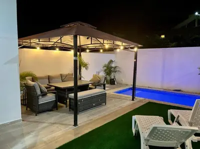 a patio with a table and chairs and an umbrella at Townhouse with Private Pool and nearby beaches in Punta Cana