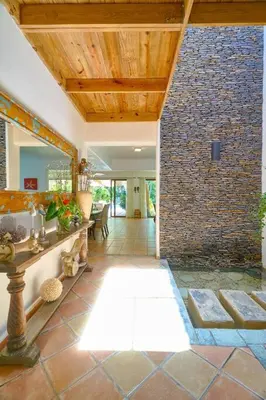 a living room with a stone wall and a hallway at Escape Beach Villa in El Portillo, Las Terrenas in Las Terrenas