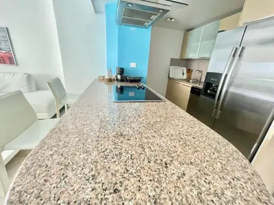 a kitchen with a granite counter top and a refrigerator at Marbella 2bedroom Beachfront Apartment in San Pedro de Macorís