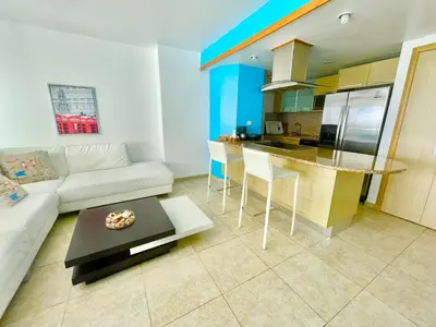 a living room with a white couch and a kitchen at Marbella 2bedroom Beachfront Apartment in San Pedro de Macorís