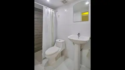 a white bathroom with a toilet and a sink at Malecon Premium Plus in Santo Domingo