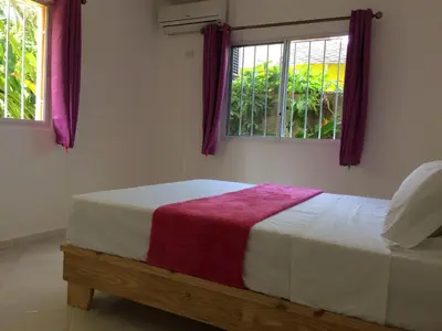 a bed in a room with two windows at Caoba in Las Terrenas