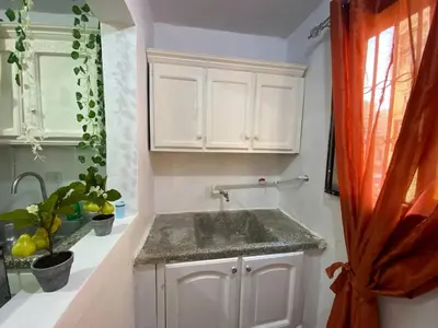 a white kitchen with a sink and a window at Dr Adorable Y Comfortable Apt para Su Disfrute in Santiago de los Caballeros