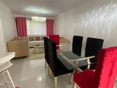 a dining room with a glass table and red chairs at 9DR 3-Bedroom Apartment Near Monumental Area in Santiago de los Caballeros