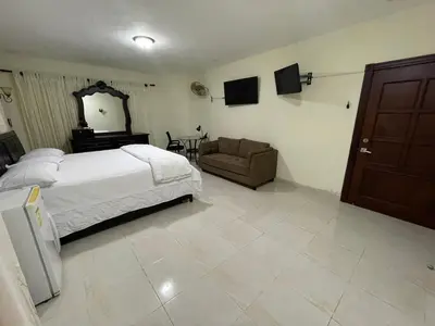 a bedroom with a bed and a chair and a mirror at Maria's Entire House HIGUEY 2BD in Higuey