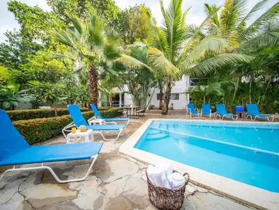 a pool with blue chairs and palm trees at Stylish 1r-1b Apt Near The Beach And Main Street in Sosúa