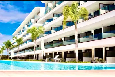 a building with a swimming pool and palm trees at Luxury Apartment With Pool And Golf View in Punta Cana