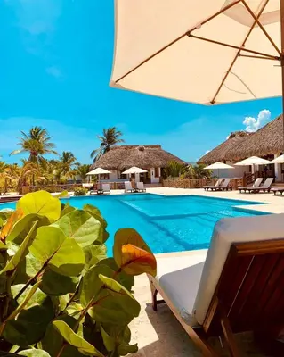 a resort swimming pool with a chair and an umbrella at Luxury Apartment With Pool And Golf View in Punta Cana