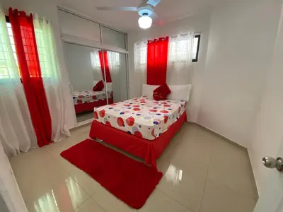a small bedroom with a bed with red curtains at Santiago Center Huge Apartment 2stay rooftop to enjoy the city view 6-3 in Santiago de los Caballeros