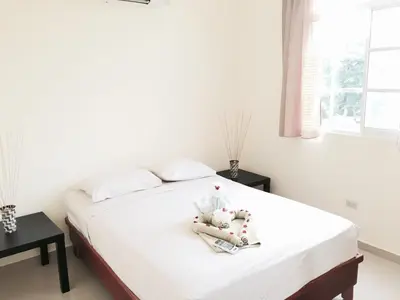 a bedroom with a bed with white sheets and a window at Costambar in San Felipe de Puerto Plata