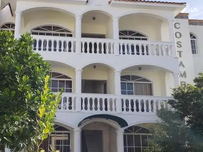 a white building with a balcony on it at Costambar in San Felipe de Puerto Plata