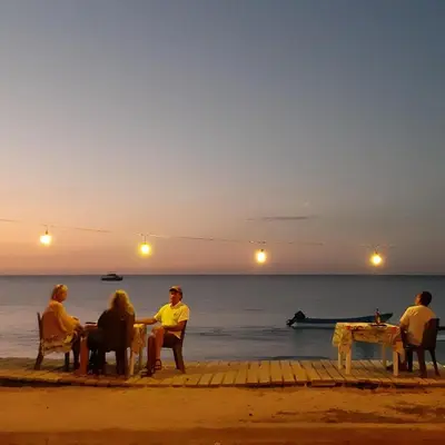 a group of people sitting at a table on the beach at Villa Rosa in Punta Rucia