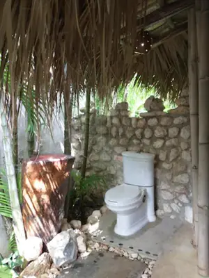 a bathroom with a toilet in a stone wall at Jungle Hut near Beach - Nature Lovers in Las Terrenas