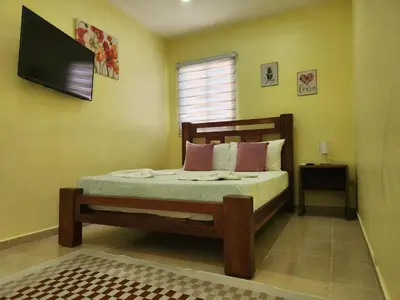 a bedroom with a bed and a flat screen tv at Apartamentos Melya cerca de la Playa Caleta in La Romana
