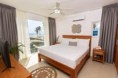 a bedroom with a bed and a television and a window at Amazing Ocean Front - 2 bedroom Apartment (117 sq meters) in Cabarete