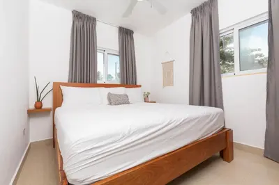 a bedroom with a bed with white sheets and windows at Amazing Ocean Front - 2 bedroom Apartment (117 sq meters) in Cabarete