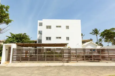 a white house with a wooden fence in front of it at Amazing Ocean Front - 2 bedroom Apartment (117 sq meters) in Cabarete