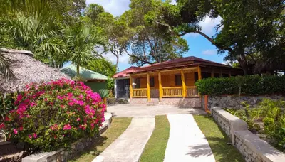 a house with a garden and flowers in front of it at Hacienda La Huerta Puerto Plata, 1 BDR in San Felipe de Puerto Plata