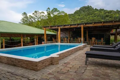 a swimming pool in a patio with chairs and a house at Hacienda La Huerta Puerto Plata, 2 BDR in Maimón