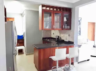 a kitchen with a counter and some white stools at Self check in , moderno, A/C completo Wifi, TV 4K in Santiago de los Caballeros
