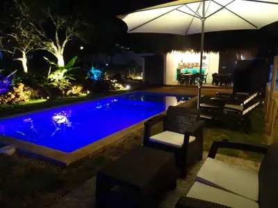 a swimming pool at night with an umbrella at BUNGALOWS COLIBRI in Las Galeras