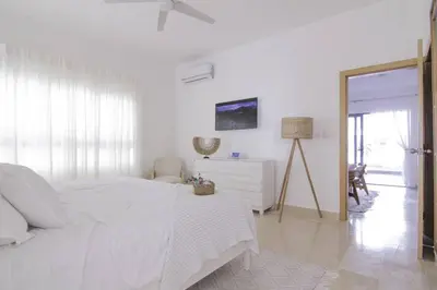 a white bedroom with a white bed and a mirror at New Beachfront Penthouse Punta Popy in Las Terrenas
