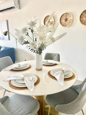 a white table with chairs and a vase of white flowers at Super Luxurious L6 Sky Blue Apartment in Santo Domingo