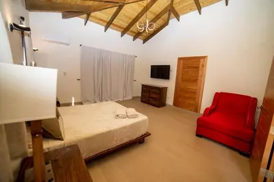 a bedroom with a bed and a red chair at ωιℓℓу'ѕ νιℓℓα in Jarabacoa