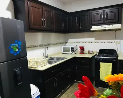 a kitchen with black cabinets and a sink and a microwave at Apartamentos ipap luperon in Puerto de Luperon