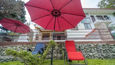 a group of chairs and umbrellas in front of a building at Peace By The River in Jarabacoa
