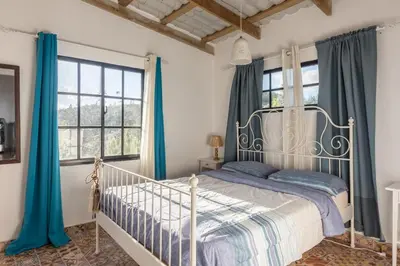 a bedroom with a white bed and blue curtains at Colonial Suite Constanza in Arroyo Frío