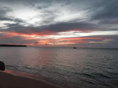 a sunset on the beach with a boat in the water at Casa merengue in Las Terrenas