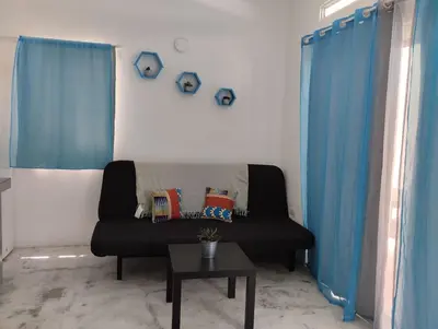 a living room with a black couch and blue curtains at Casa merengue in Las Terrenas