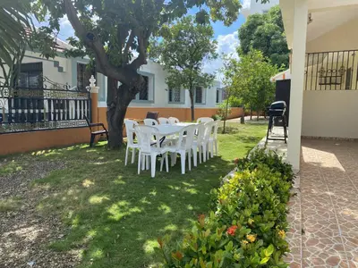 a table and chairs in a yard with a tree at Casa Corona Plaza in Santiago de los Caballeros