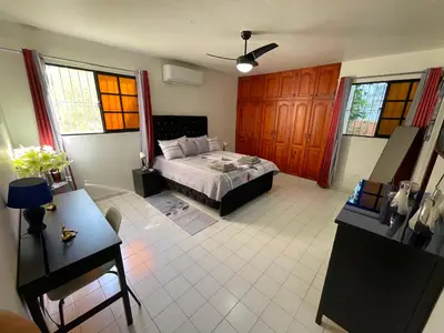a bedroom with a bed and a table and windows at Casa Corona Plaza in Santiago de los Caballeros