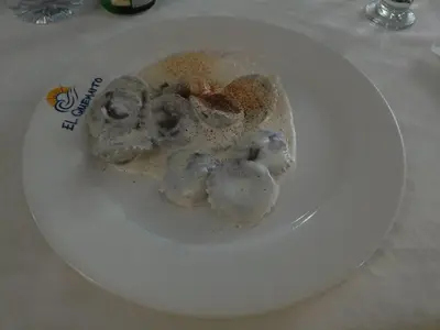 a white plate with mushrooms on a table at Hotel El Quemaito - Luxury Oceanfront Retreat in Santa Cruz de Barahona