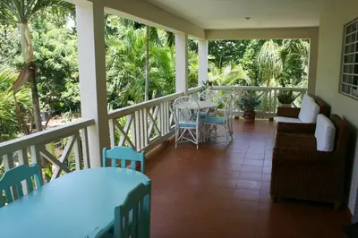 a porch with chairs and a table on a balcony at Costambar Tropical Garden in San Felipe de Puerto Plata