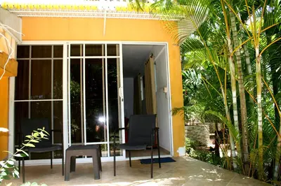 a patio with two chairs and a table in front of a house at Costambar Tropical Garden in San Felipe de Puerto Plata