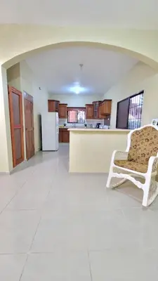 an empty living room with a chair and a kitchen at Jarabacoa Mountain Views in Jarabacoa
