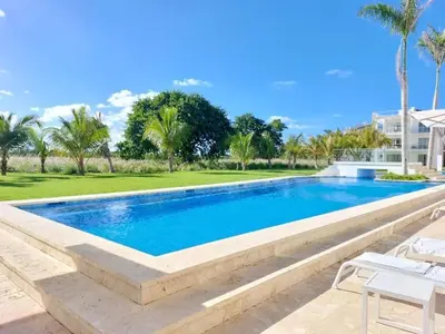 a swimming pool in a resort with palm trees at Luxury Condo with Golf Cart Included in Cana Pearl in Punta Cana