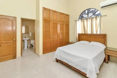 a bedroom with a bed and a bathroom at Spacious 3BR APMT- smart speakers Airport transfer in Sosúa